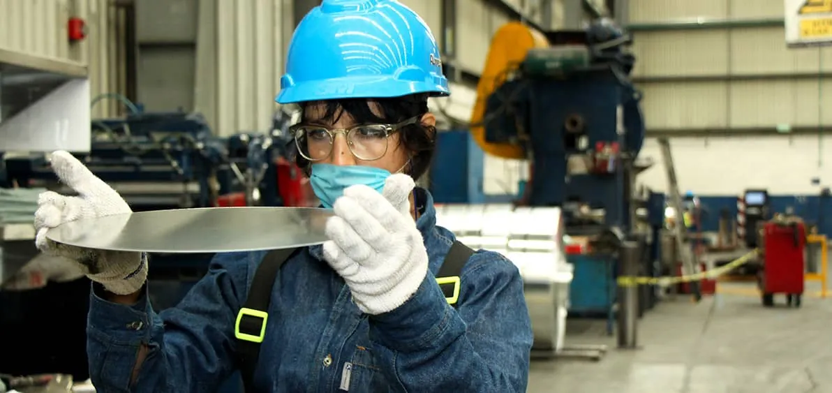 Operadora de Almexa revisando una lámina de aluminio